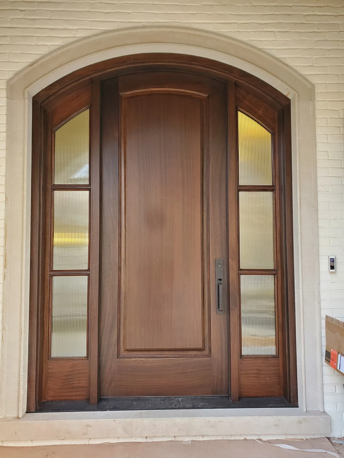 Finished wood arched entrance with textured glass sidelights